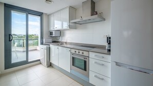 Una cucina moderna con mobili bianchi, forno a microonde integrato, piano cottura e lavastoviglie.