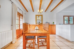 A dining area with a wooden table, chairs, a chandelier, and a large mirror.