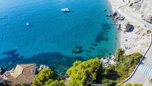 A coastal area with clear blue waters, rocky beach, and a road curving along the shore. - Villa "Casa San Cayetano" with Sea View, Pool, Garden, Terrace and Balcony (La Herradura)