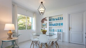 A dining area with a round glass table, white chairs, a lamp, and blue vases on shelves. - Villa "Casa San Cayetano" with Sea View, Pool, Garden, Terrace and Balcony (La Herradura)