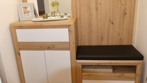 A wooden bench with a black seat, a white cabinet with two doors, and a small table with a framed picture and decorative items. - Apartment Siegl by Interhome (Zell am See)