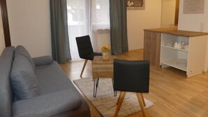 A modern living room with a grey sofa, two black chairs, a wooden coffee table, and a wooden cabinet with shelves. - Apartment Siegl by Interhome (Zell am See)