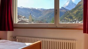 A room with a bed, a window with a mountain view, and a radiator. - Beaulieu by Interhome (Zermatt)
