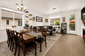 Amplia sala de estar con mesa de comedor, sillas, sofás y chimenea.