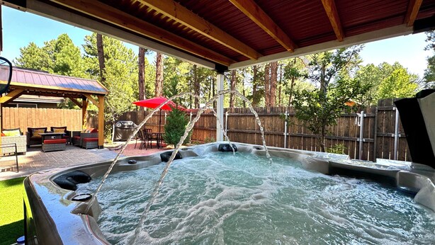 Un bain à remous avec une terrasse en bois et un espace patio couvert.