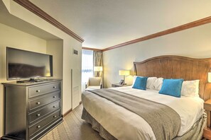Une chambre d’hôtel avec un grand lit, une commode, une télévision et une table de chevet avec une lampe.