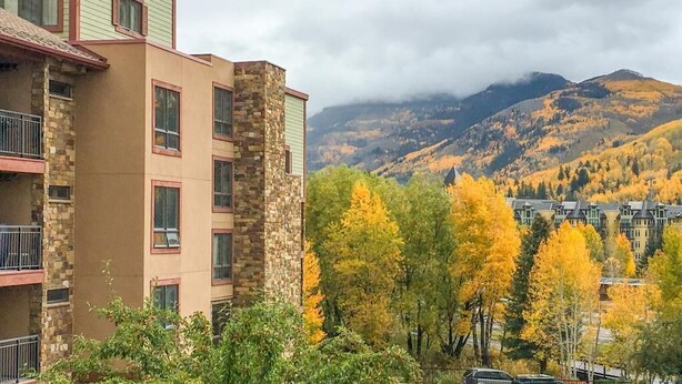 Un edificio a più piani con facciata in pietra e una parte superiore verde.