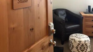 Una porta in legno con un'insegna 'Vail Haus Studio', una poltrona in pelle nera, un tavolino in legno e un elemento decorativo a parete.