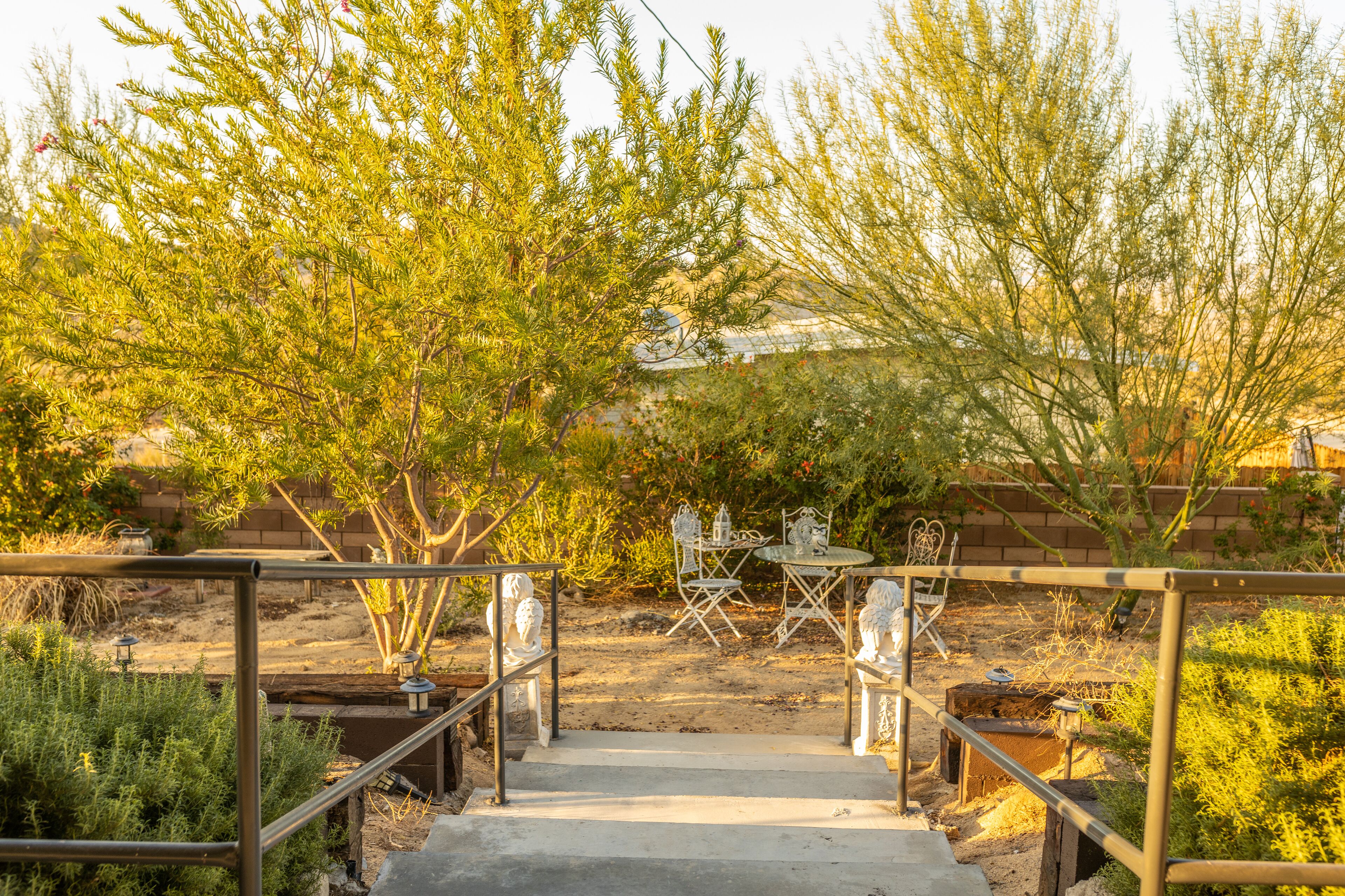 A patio area with a metal railing, a concrete staircase, and outdoor furniture including a table and chairs.