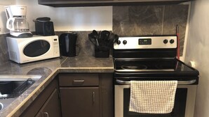 Una cocina con microondas, cafetera y estufa.