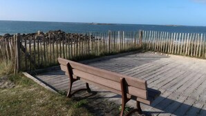 A wooden bench on a wooden deck overlooking a beach with a wooden fence in the foreground. - Les Dunes by Interhome (Saint Pabu)