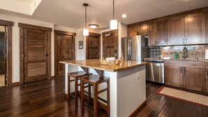 Une cuisine moderne avec des meubles en bois, un réfrigérateur en acier inoxydable et un plan de travail en granit.
