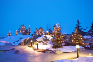 A snow-covered outdoor area with illuminated Christmas trees and a staircase leading up to a building. - June Dates Just Opened at Great Rates! Pool/Hot Tub (Steamboat Springs)