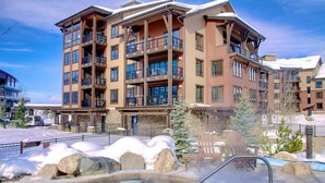 Un hôtel à plusieurs étages doté de balcons, d’un espace piscine et, au loin, d’une piste de ski.