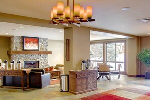 A spacious living area with a fireplace, a large window, and a modern chandelier.