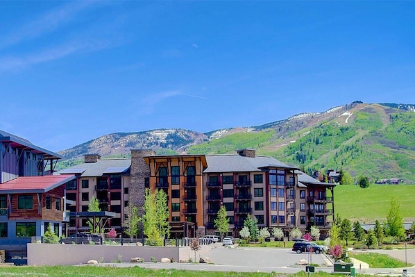 A multi-story hotel with a central courtyard, surrounded by lush greenery and mountains in the background.