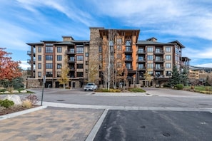 A multi-story hotel with a central courtyard, a parking area, and a mountain view.