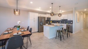 A modern kitchen with white cabinets, stainless steel appliances, and a central island with bar stools.