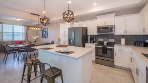 A modern kitchen with white cabinets, stainless steel appliances, and a central island.