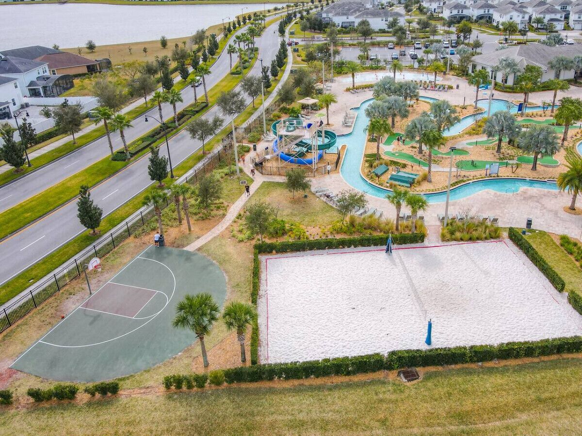 Vue aérienne d’un quartier résidentiel avec un terrain de basketball, une piscine et une route.