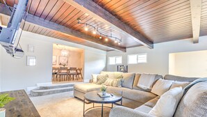 A spacious living room with a large sectional sofa, a round coffee table, and a dining area with a chandelier. - Home near Calistoga w/ heated pool & hot tub (Santa Rosa)