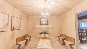 A dining area with a long table, wooden chairs, a chandelier, and artwork on the walls. - Home near Calistoga w/ heated pool & hot tub (Santa Rosa)