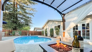 A backyard with a swimming pool, a fire pit, outdoor furniture, and a bottle of wine. - Home near Calistoga w/ heated pool & hot tub (Santa Rosa)