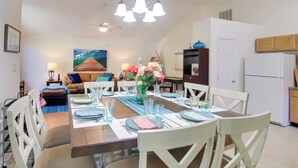 A dining area with a wooden table set for four, surrounded by white chairs. There is a chandelier above the table, and a painting on the wall behind the dining area. - Pool, Trail Access! Dog-Friendly Ocean Pines Haven (Ocean Pines)