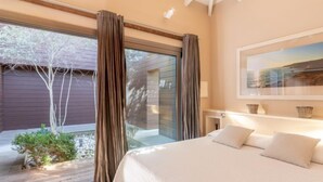 A modern bedroom with a large bed, a view of the outdoors, and a painting on the wall. - Villa Lavezzi by Interhome (Bonifacio)