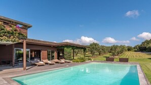 A modern poolside area with a clear pool, wooden deck, and lounge chairs. - Villa Lavezzi by Interhome (Bonifacio)