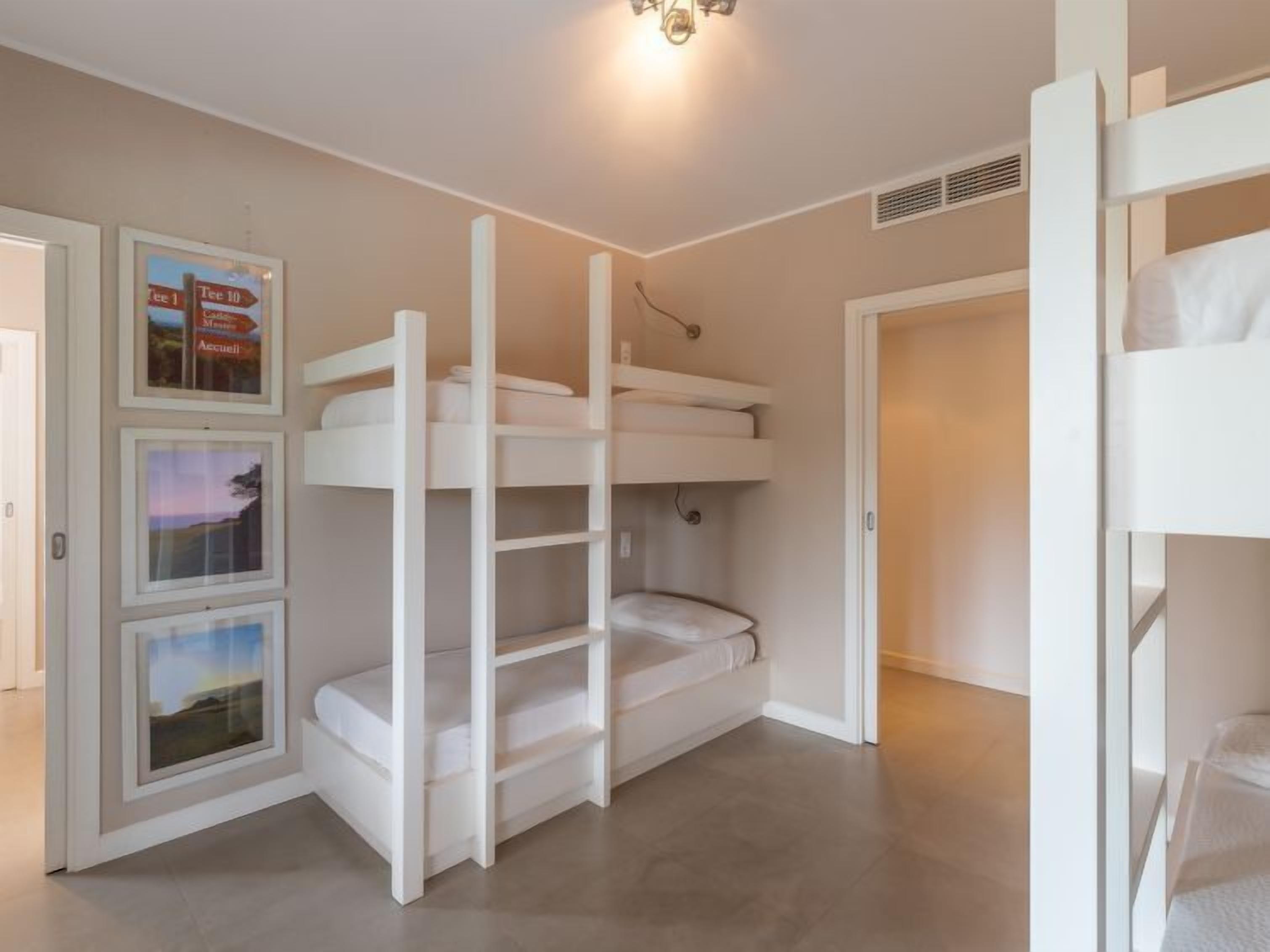 Habitació amb llits superposats, un cartell amb indicacions i una porta que dona a una altra habitació.