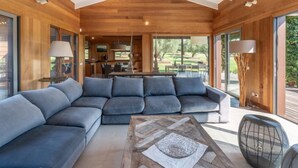A modern living room with a sectional sofa, a coffee table, and a dining area visible through large windows. - Villa Lavezzi by Interhome (Bonifacio)