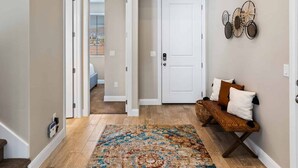 A spacious hallway with a patterned rug, a bench with cushions, and mounted animal heads on the wall. - The Jungalow by RedAwning (Washington)