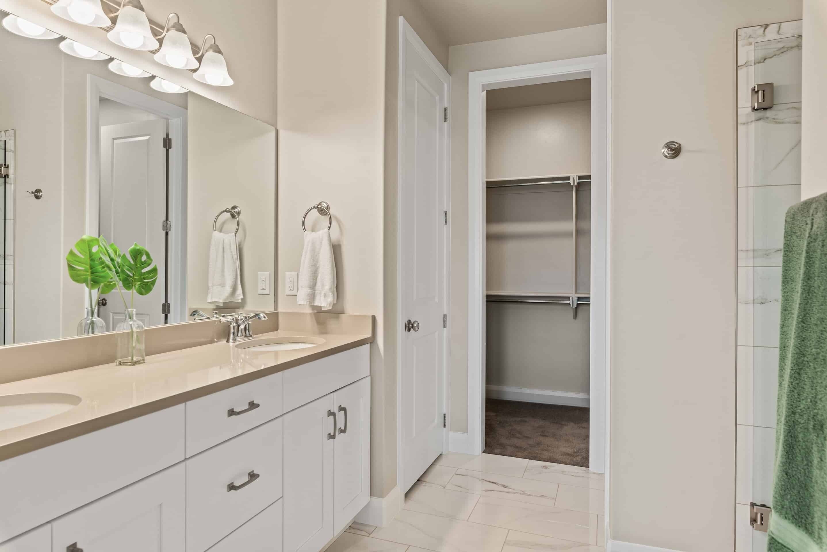 A modern bathroom with a double sink vanity, a large mirror, and a walk-in shower.