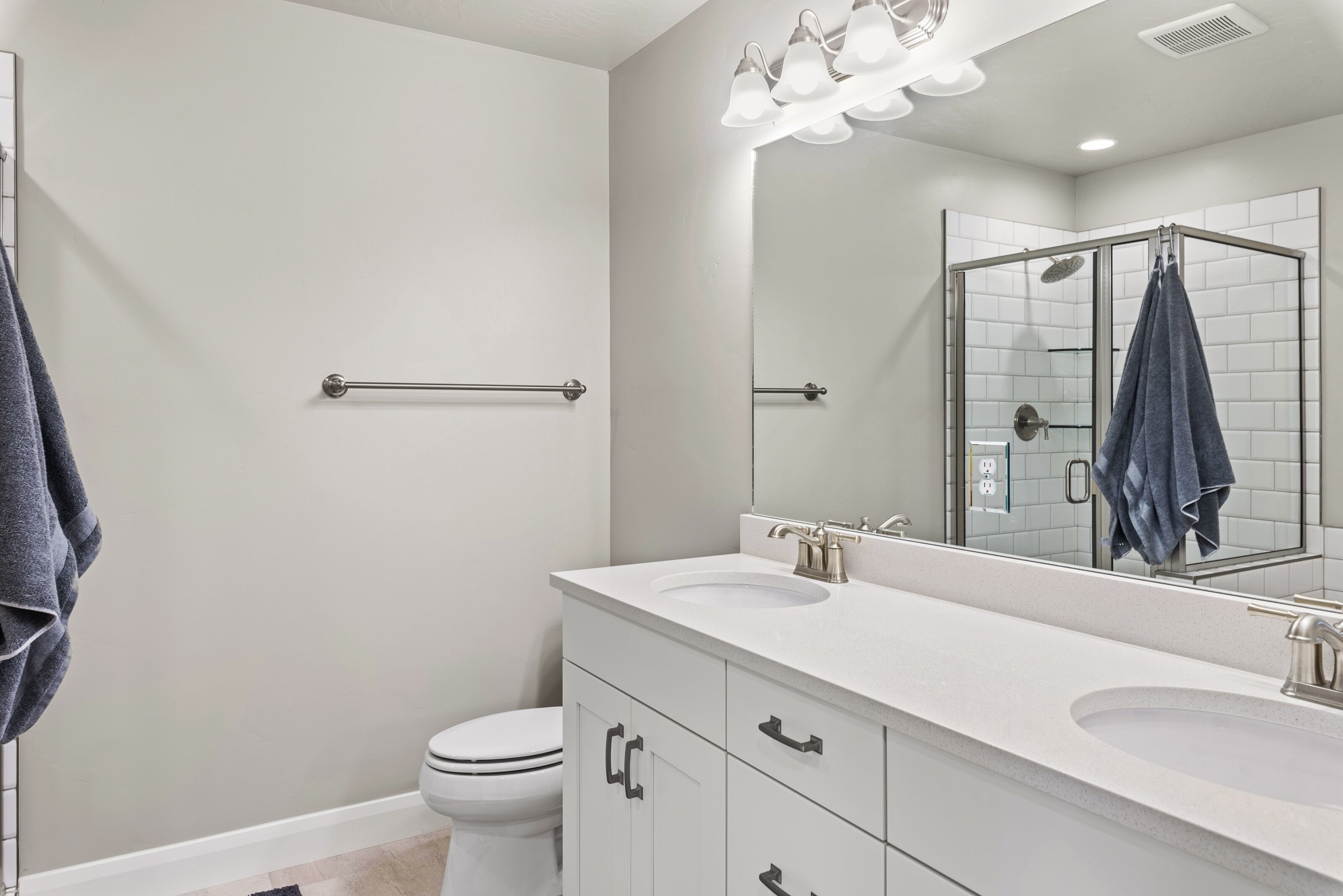 A modern bathroom with a white sink, a large mirror, and a shower enclosure.