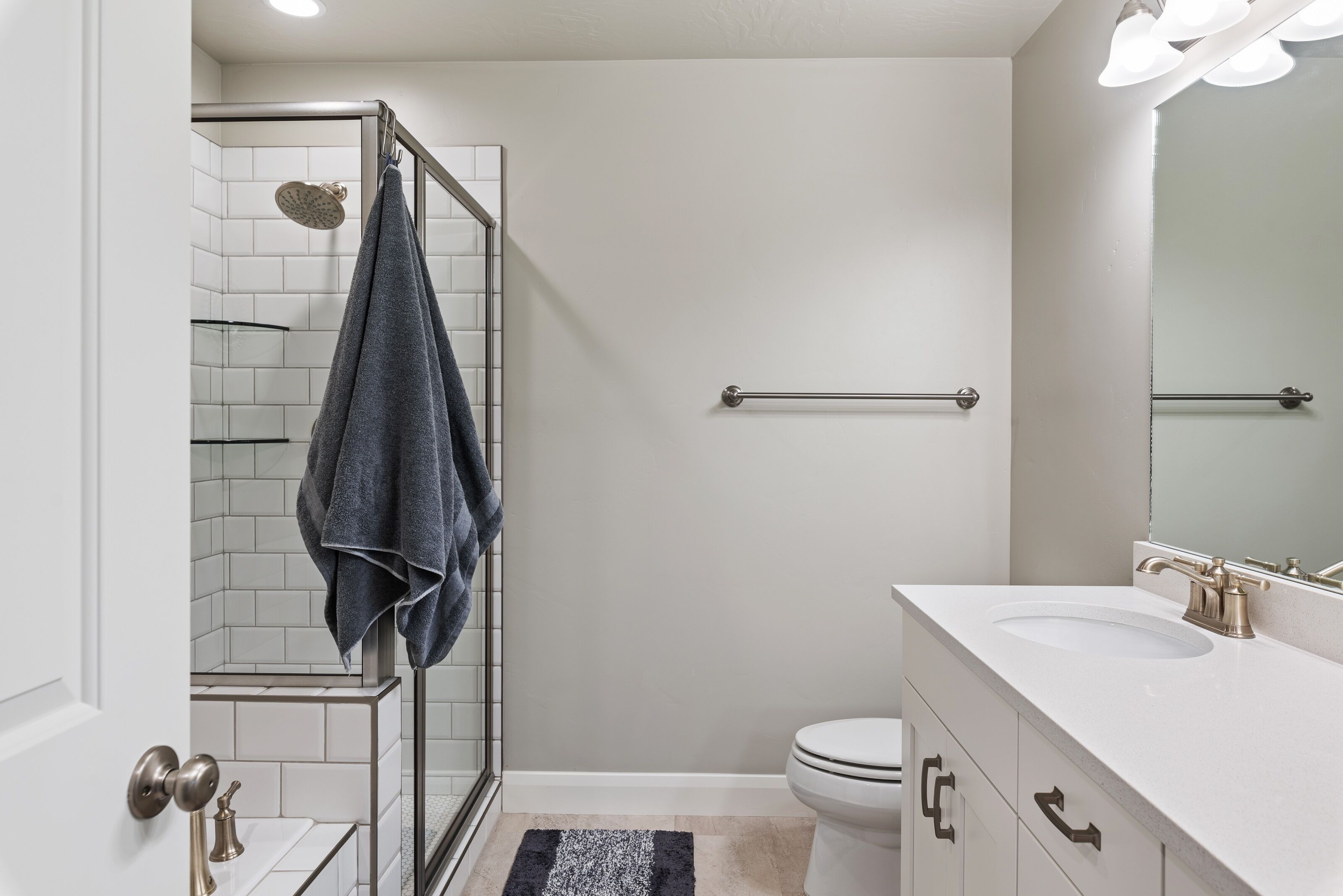 Un baño moderno con cabina de ducha de vidrio, un lavamanos blanco y un inodoro.