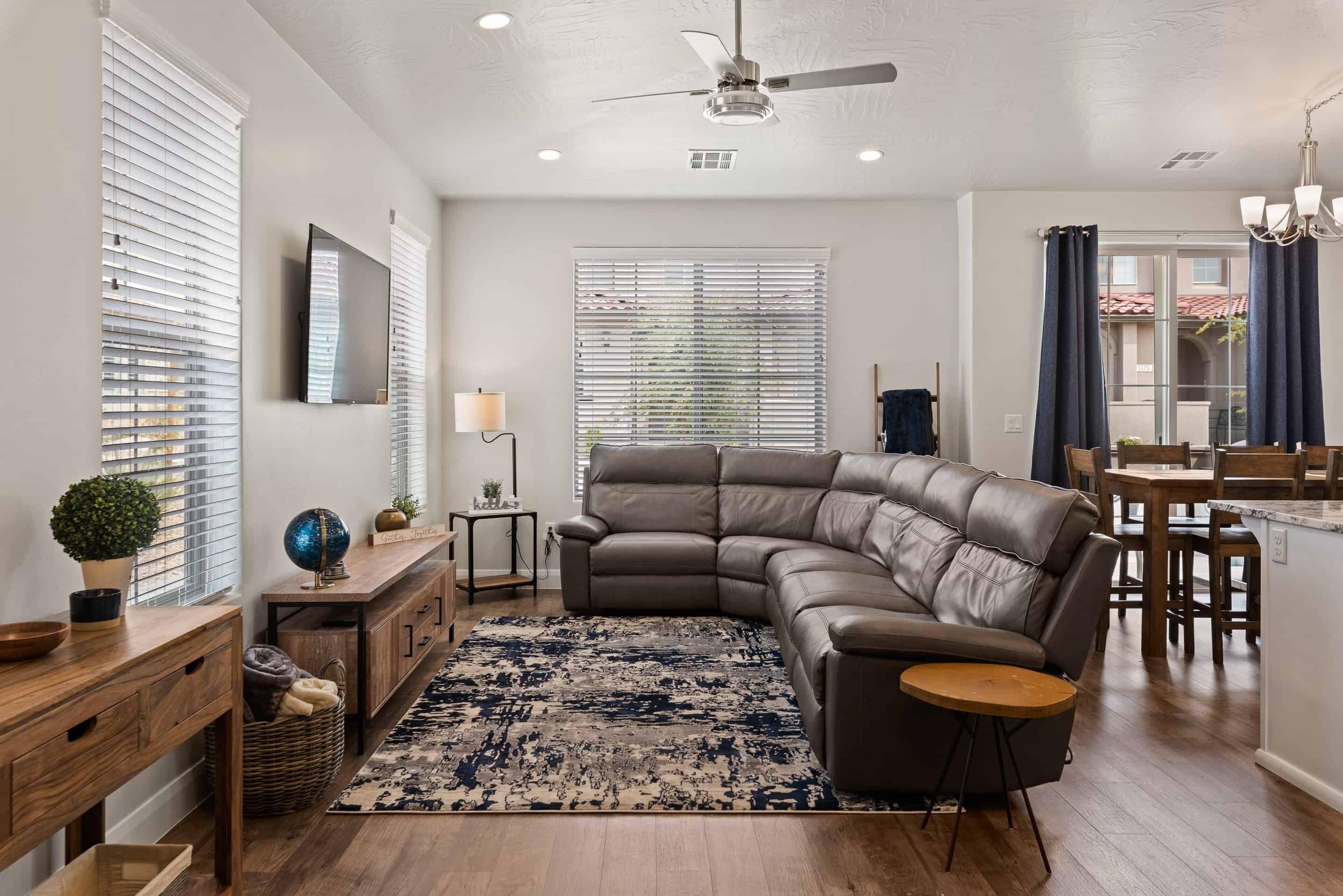 A modern living room with a sectional sofa, a wooden coffee table, a floor lamp, and a large rug.