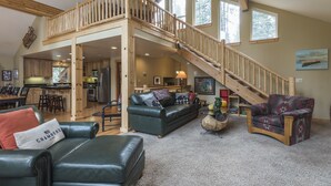 A spacious living area with a high ceiling, wooden staircase, and a view of the kitchen and dining area. - Beautiful Chamberlands home w/ full access to private Chamberlands pool, beach, and tennis (Tahoma)