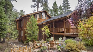 A cabin with a deck and a flag, surrounded by trees and a garden. - Beautiful Chamberlands home w/ full access to private Chamberlands pool, beach, and tennis (Tahoma)