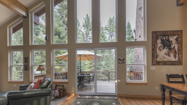 A spacious living room with large windows, a green leather sofa, a wooden dining table, and a rug with a geometric pattern. - Beautiful Chamberlands home w/ full access to private Chamberlands pool, beach, and tennis (Tahoma)