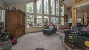 A spacious living room with large windows, a wooden cabinet, a leather sofa, and a glass coffee table. - Beautiful Chamberlands home w/ full access to private Chamberlands pool, beach, and tennis (Tahoma)