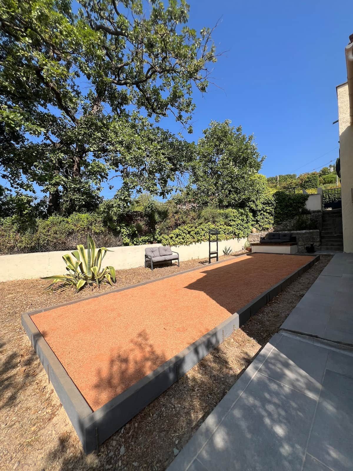 A courtyard with a seating area, a pergola, and a stone wall.