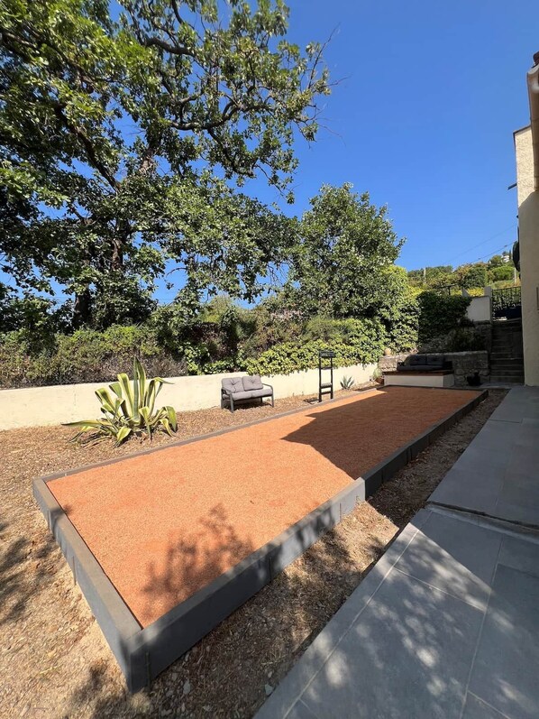 A courtyard with a seating area, a pergola, and a stone wall.