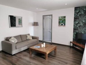A modern living room with a sofa, coffee table, and a television on a stand.