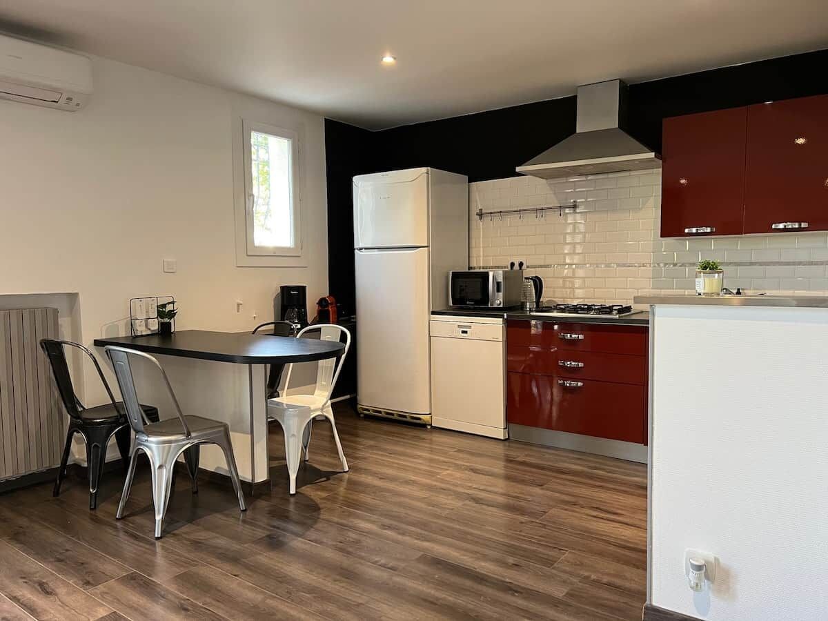 A modern kitchen with a dining area, featuring a refrigerator, microwave, stove, and a dining table with chairs.