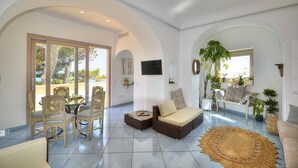A spacious living area with a dining table, chairs, a sofa, and a TV. - Villa Flaviana: An elegant and welcoming three-story villa built sheer above the sea, with Free WI-FI. (Praiano)