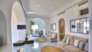 A spacious living room with a large sofa, a smaller sofa, and a coffee table. There are two large woven rugs on the floor. - Villa Flaviana: An elegant and welcoming three-story villa built sheer above the sea, with Free WI-FI. (Praiano)