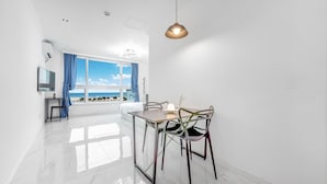 A modern, bright room with a large window offering a view of the beach, a dining table with chairs, and a hanging light fixture. - Hi Yeongjin Spa Pension (Gangneung)
