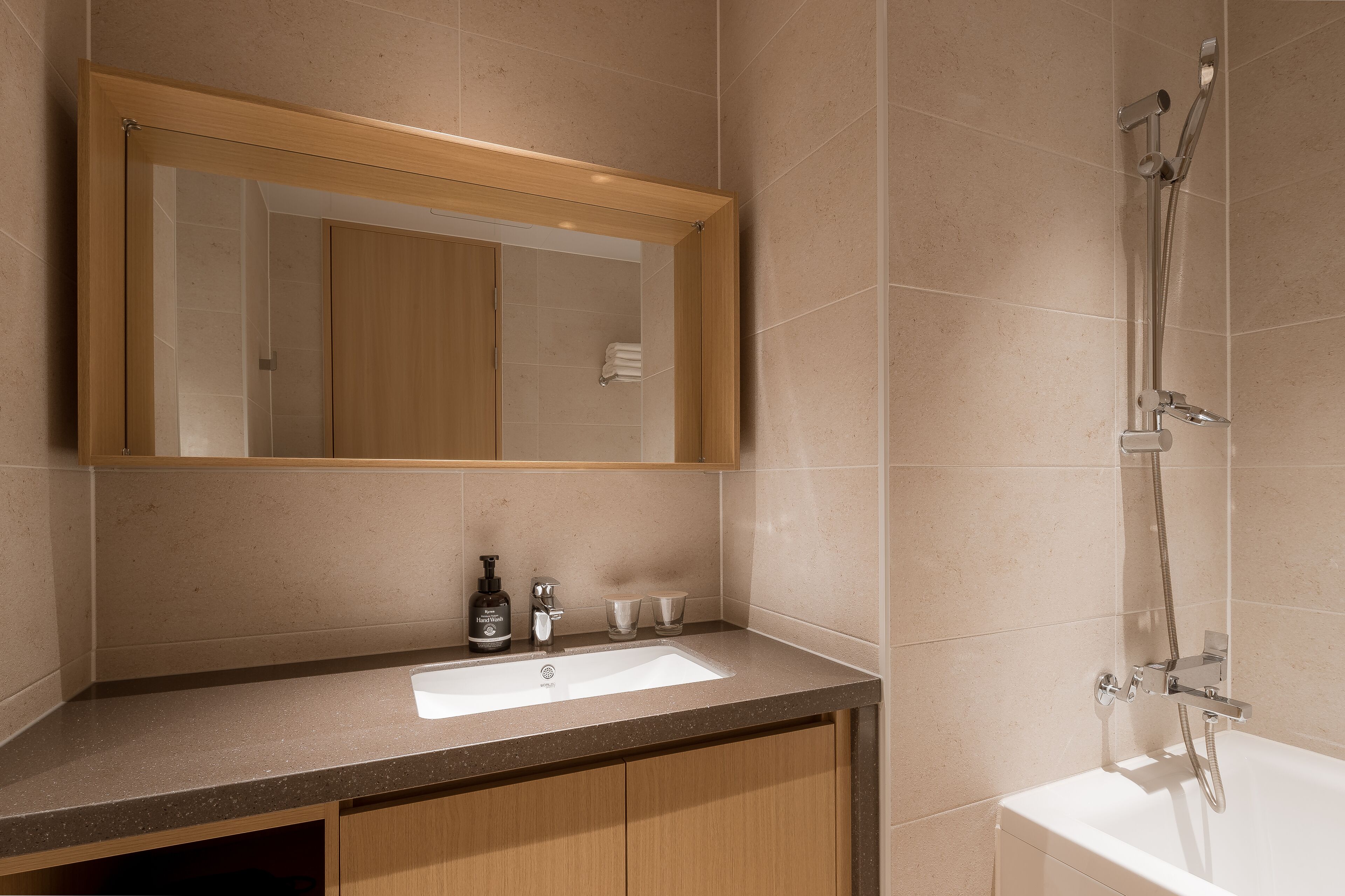 A bathroom with a wooden vanity, a sink, a mirror, and a shower.