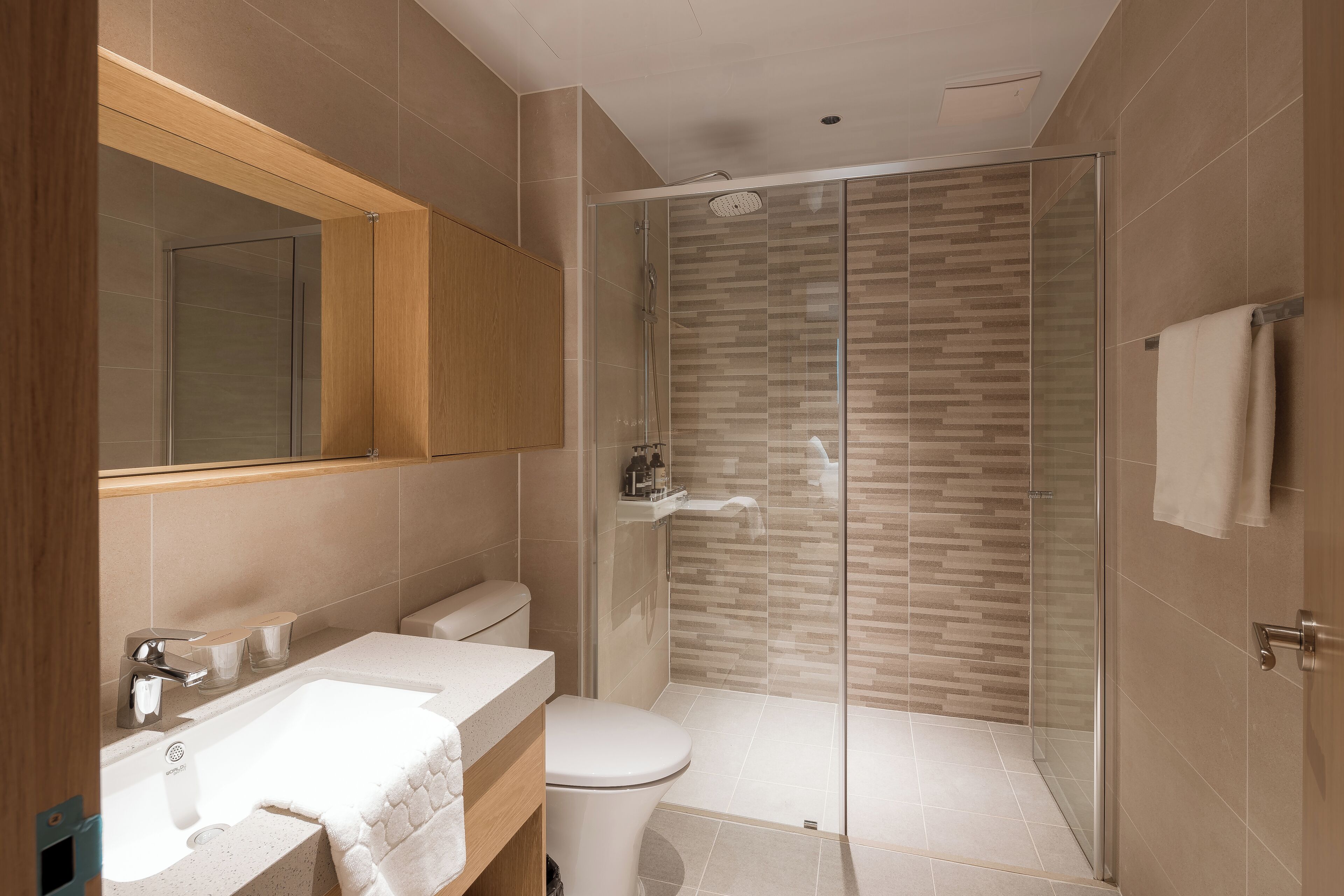 A modern bathroom with a glass-enclosed shower, a wooden vanity, and a large mirror.